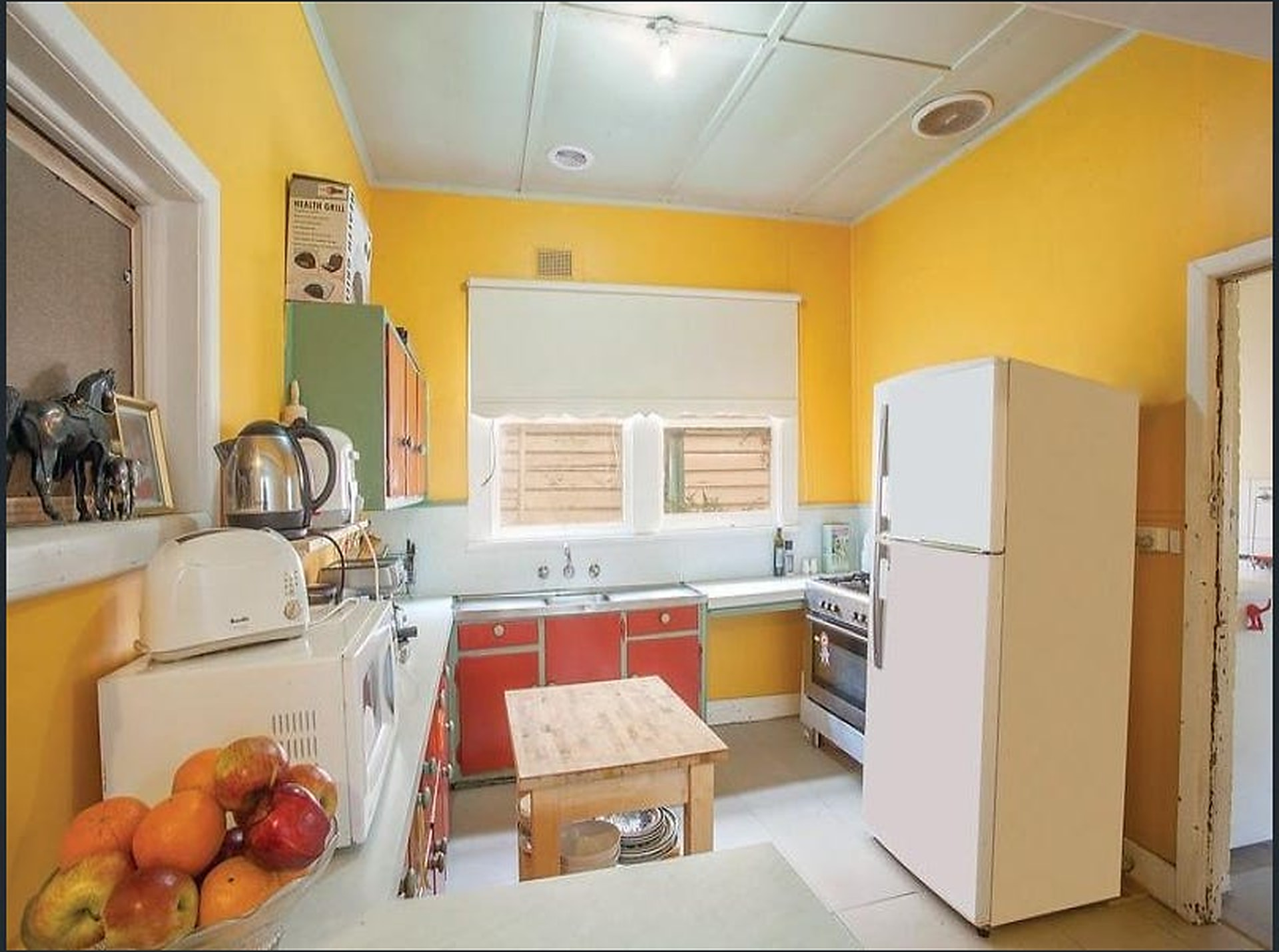 Original cottage kitchen with dated cabinetry and strong wall colour