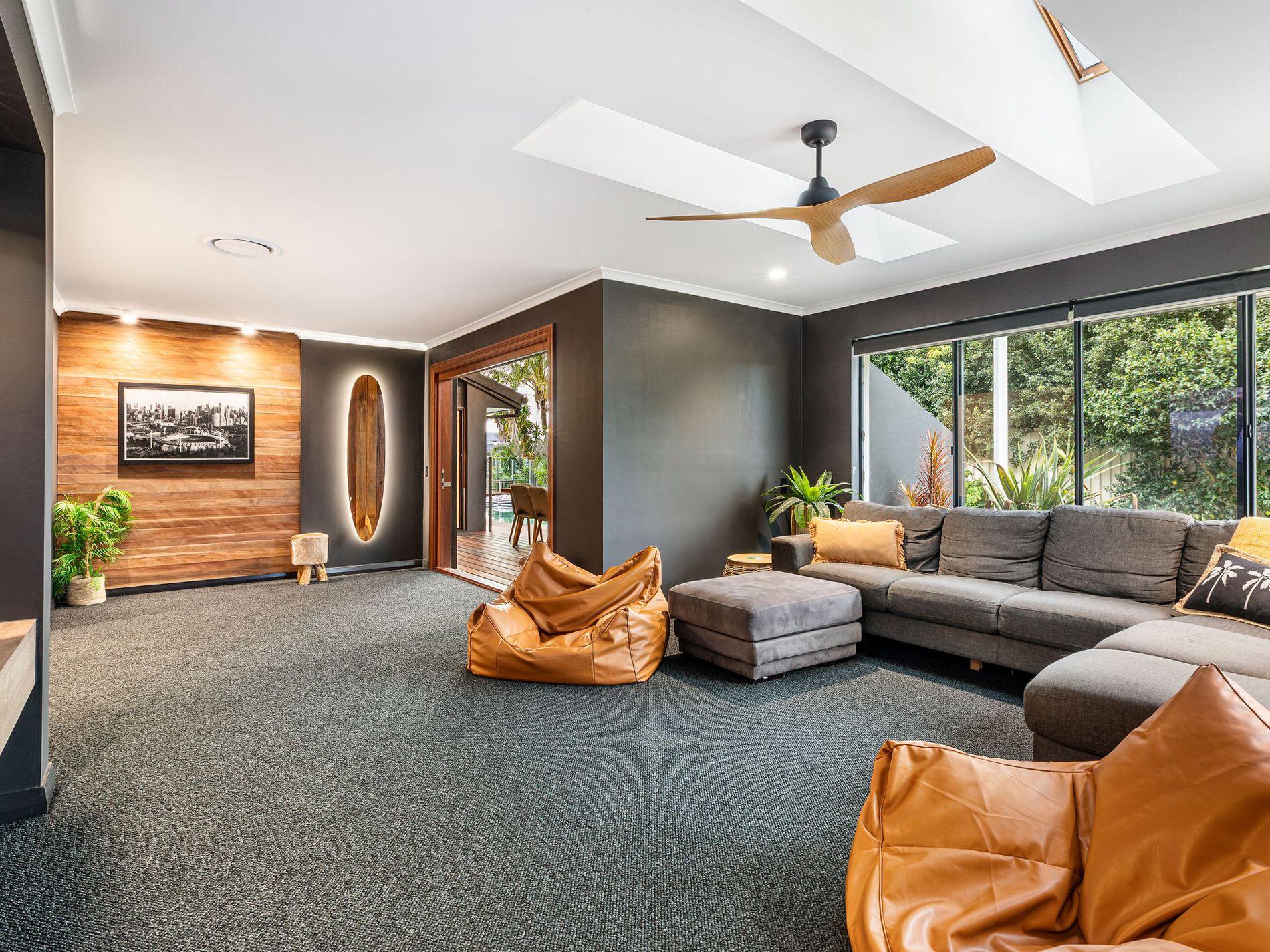Finished media room with leather bean bags, grey sofa, timber feature wall and garden outlook
