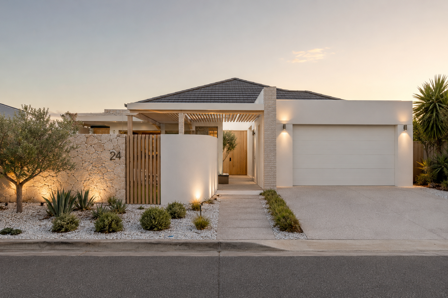 Modern single-storey home facade at dusk with stone wall, timber entry and landscaped front garden